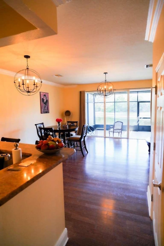 dining area with dark wood finished floors, a notable chandelier, visible vents, and ornamental molding