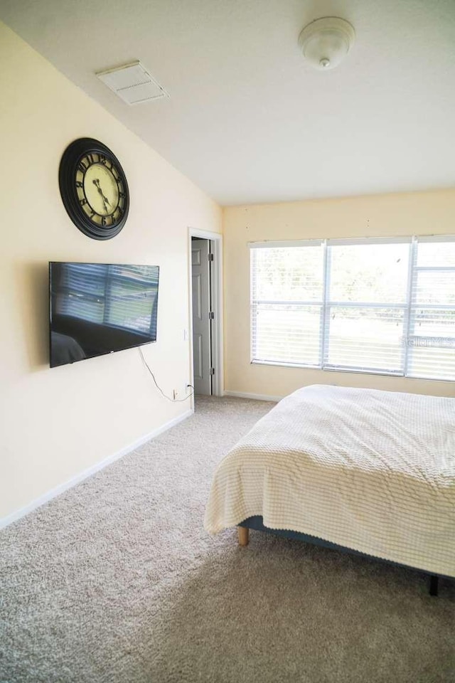 unfurnished bedroom featuring baseboards, lofted ceiling, carpet, and visible vents