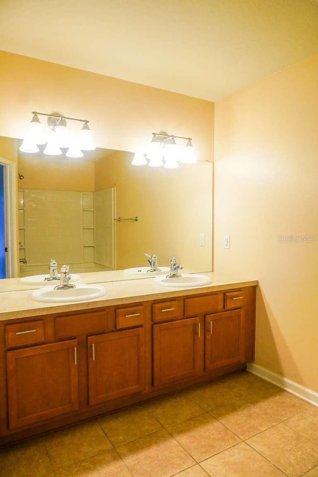 full bath featuring a sink, baseboards, double vanity, and tile patterned flooring