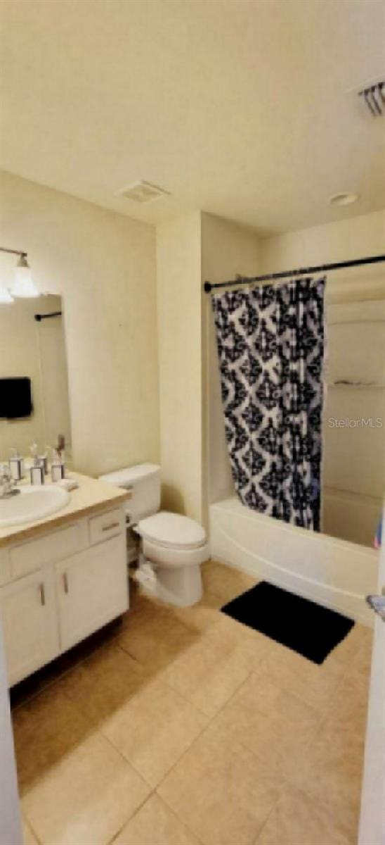 bathroom featuring visible vents, shower / bath combo with shower curtain, toilet, tile patterned flooring, and vanity