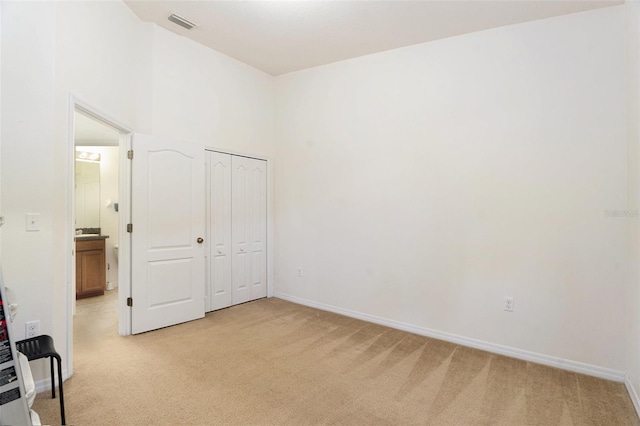 unfurnished bedroom with light carpet, a closet, visible vents, and baseboards