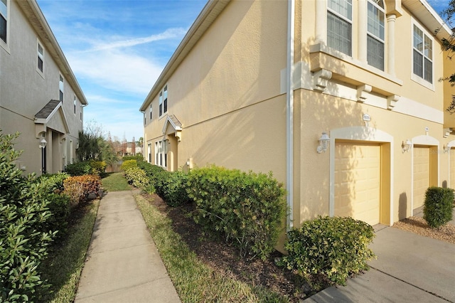 view of side of property featuring an attached garage and stucco siding