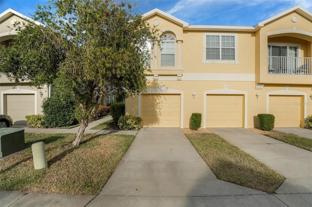 multi unit property with driveway, a garage, and stucco siding