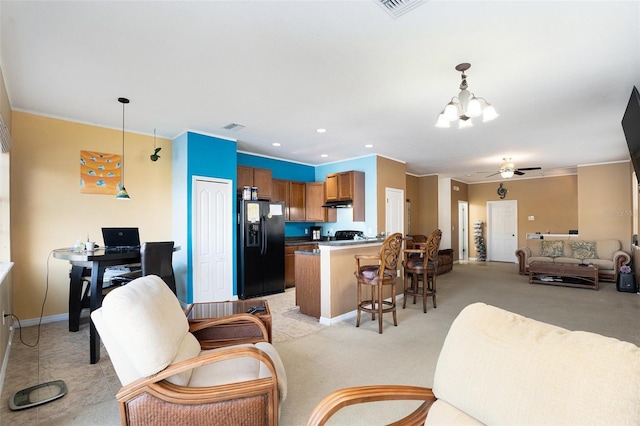 kitchen with brown cabinetry, light colored carpet, open floor plan, decorative light fixtures, and black fridge