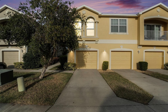 view of property with driveway, a garage, and stucco siding