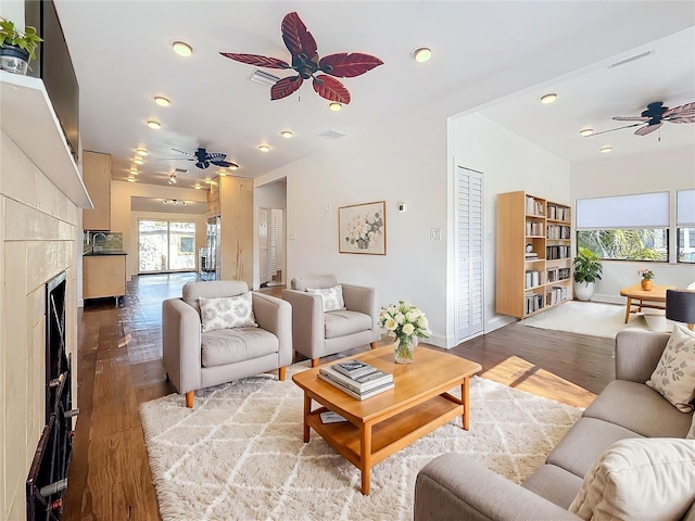 living room featuring hardwood / wood-style flooring, ceiling fan, sink, and a fireplace