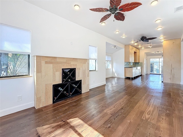 unfurnished living room featuring plenty of natural light, dark wood-type flooring, and ceiling fan