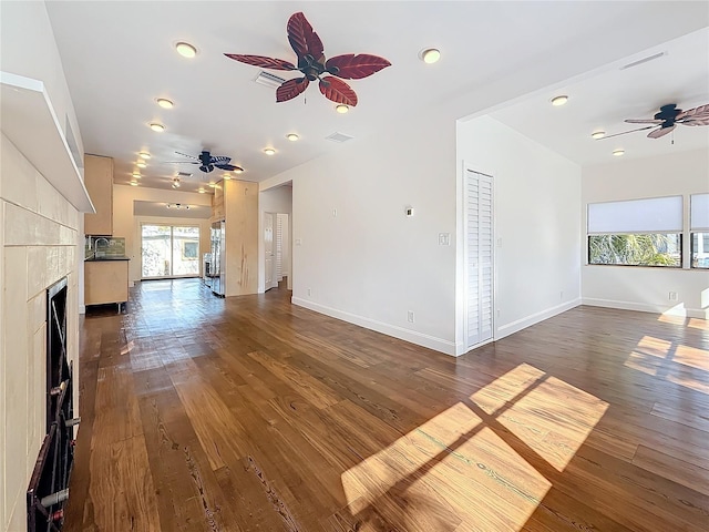 unfurnished living room featuring ceiling fan, dark hardwood / wood-style floors, sink, and a fireplace