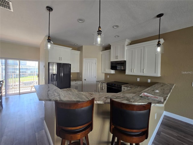 kitchen with white cabinetry, black electric range oven, stainless steel fridge, and kitchen peninsula