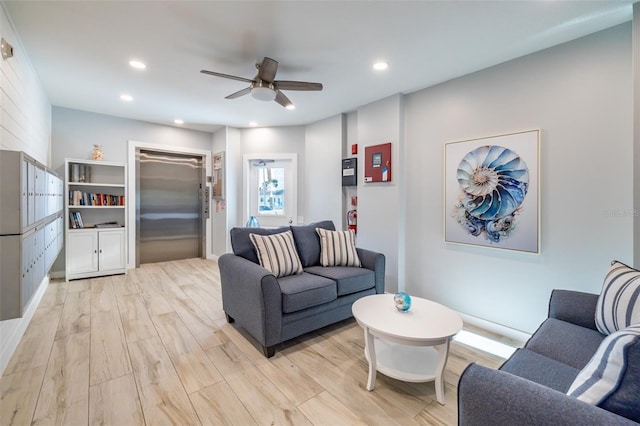 living room with ceiling fan, elevator, and light wood-type flooring