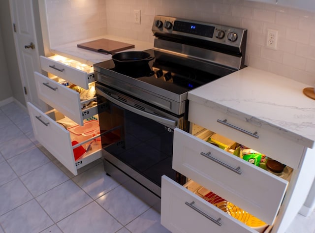 kitchen featuring white cabinetry, decorative backsplash, light tile patterned floors, electric range, and light stone countertops