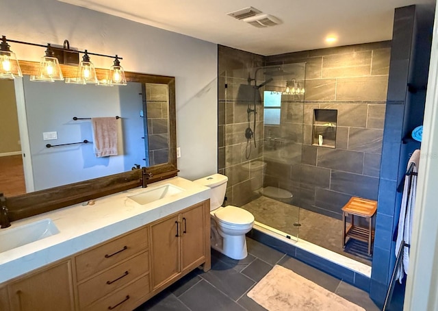 bathroom with tile patterned flooring, vanity, a tile shower, and toilet