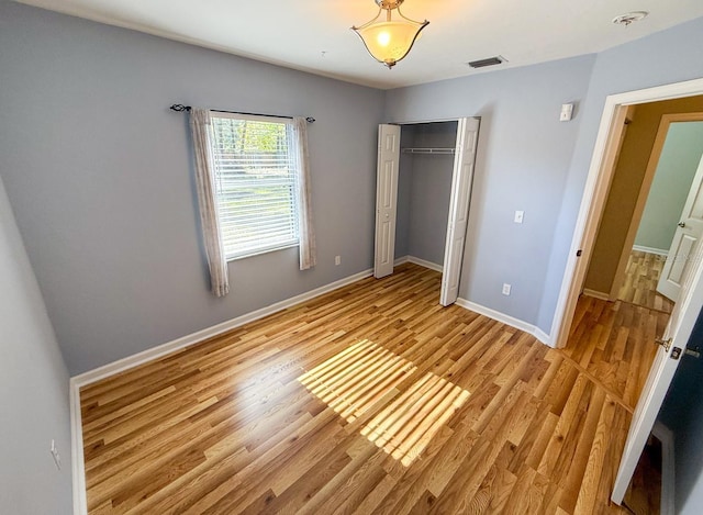 unfurnished bedroom with light wood-type flooring and a closet