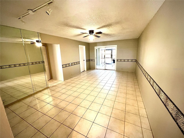 unfurnished room with track lighting, light tile patterned floors, a textured ceiling, and ceiling fan