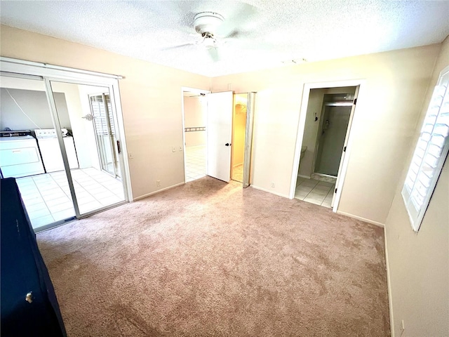 unfurnished bedroom with light colored carpet, access to outside, a textured ceiling, and washing machine and clothes dryer