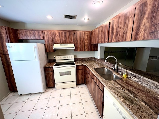 kitchen with white appliances, dark stone counters, sink, and light tile patterned floors