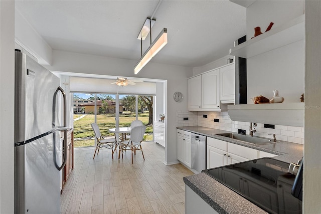 kitchen with appliances with stainless steel finishes, tasteful backsplash, white cabinetry, sink, and light hardwood / wood-style floors