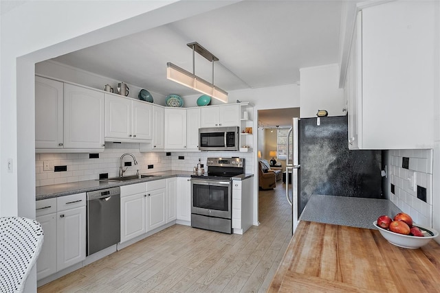 kitchen with white cabinetry, appliances with stainless steel finishes, light hardwood / wood-style floors, and sink