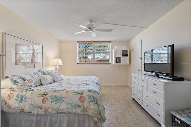 bedroom with ceiling fan, light hardwood / wood-style flooring, and a textured ceiling