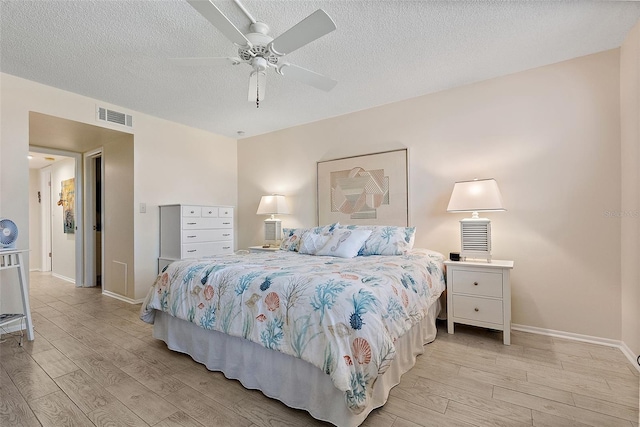 bedroom featuring ceiling fan, light hardwood / wood-style flooring, and a textured ceiling