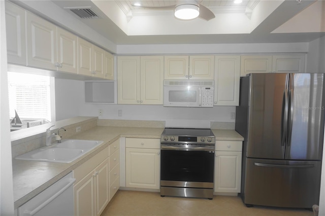 kitchen featuring stainless steel appliances, crown molding, a raised ceiling, and sink