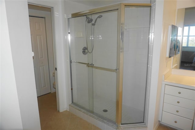 bathroom with a shower with door, vanity, tile patterned flooring, and toilet