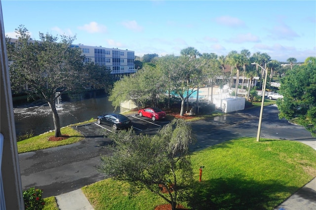 view of parking / parking lot featuring a water view and a lawn