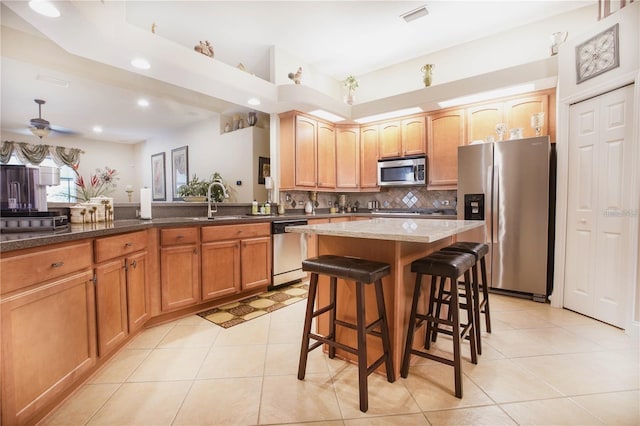 kitchen with stone counters, stainless steel appliances, a kitchen breakfast bar, tasteful backsplash, and a kitchen island