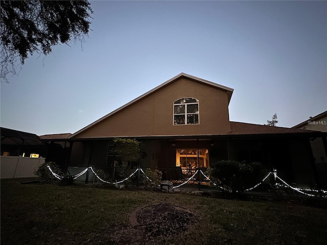 back house at dusk featuring a lawn