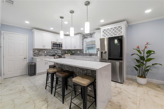 kitchen with a breakfast bar, appliances with stainless steel finishes, white cabinetry, hanging light fixtures, and a center island