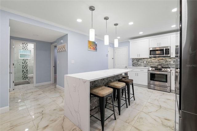 kitchen featuring crown molding, stainless steel appliances, a center island, white cabinets, and a kitchen bar