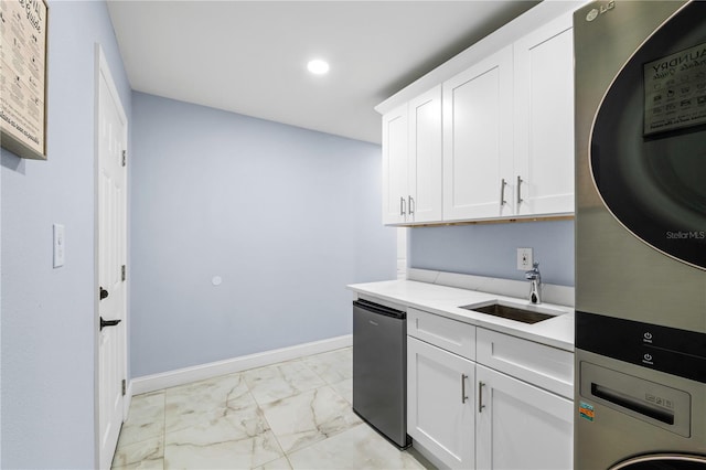 kitchen featuring white cabinetry, dishwasher, sink, stacked washer / drying machine, and light stone counters