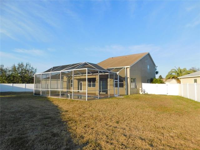 rear view of property with glass enclosure and a lawn