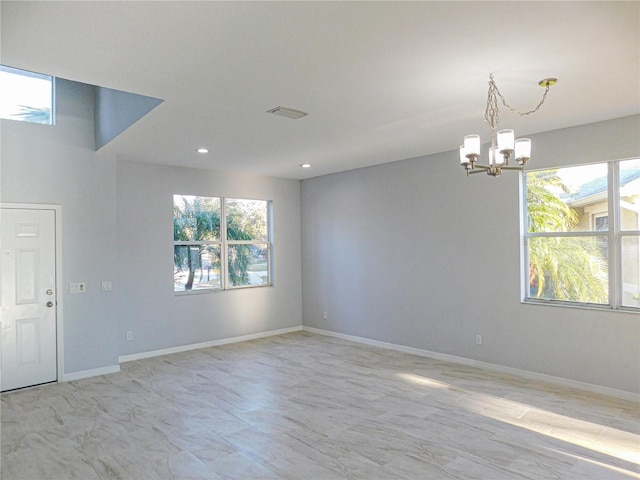 spare room featuring a wealth of natural light and a chandelier