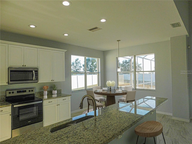 kitchen featuring decorative light fixtures, white cabinets, and appliances with stainless steel finishes