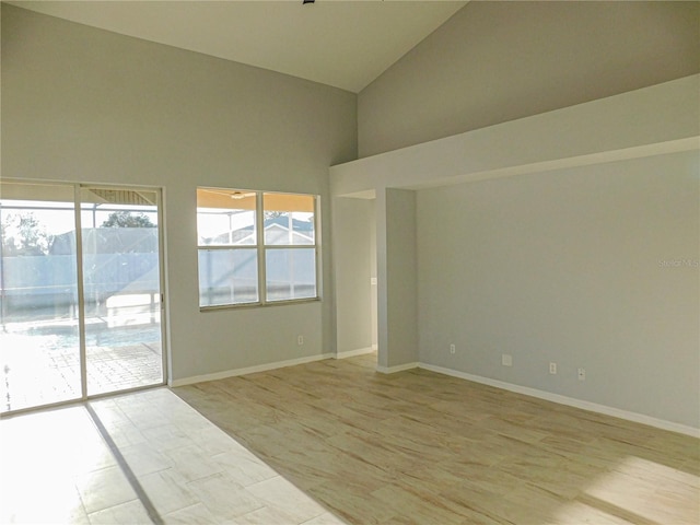 unfurnished room with high vaulted ceiling