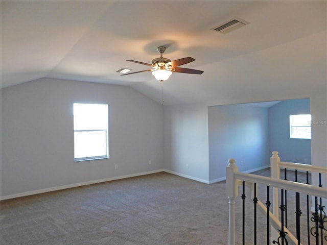 additional living space with lofted ceiling, carpet floors, plenty of natural light, and ceiling fan