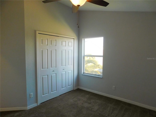 unfurnished bedroom with ceiling fan, dark carpet, and a closet