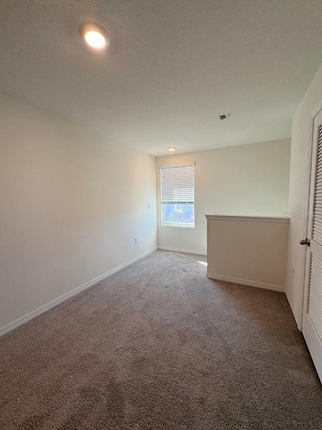 empty room with a textured ceiling and carpet flooring