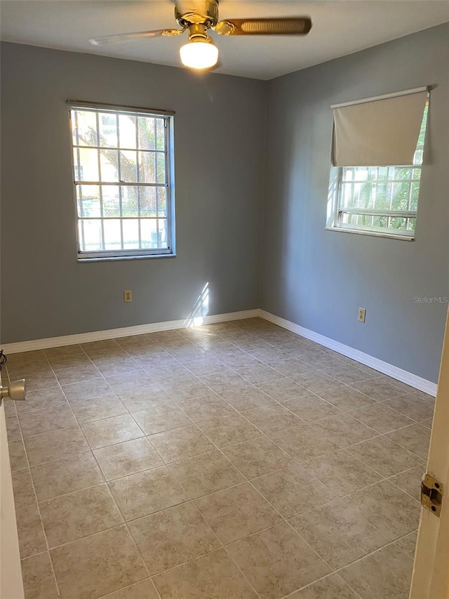 empty room with ceiling fan and light tile patterned floors