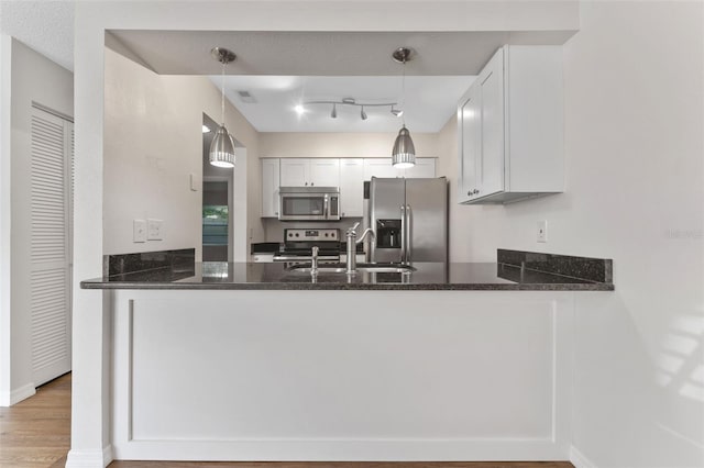 kitchen with stainless steel appliances, kitchen peninsula, sink, and white cabinets