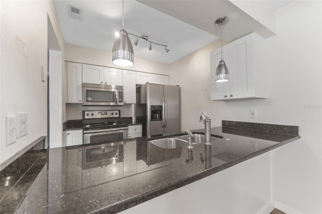 kitchen featuring sink, decorative light fixtures, dark stone countertops, stainless steel appliances, and white cabinets