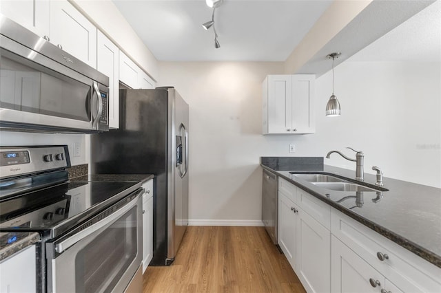 kitchen with pendant lighting, sink, white cabinetry, stainless steel appliances, and light wood-type flooring