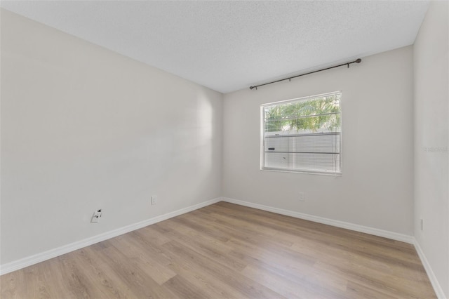 spare room with light hardwood / wood-style floors and a textured ceiling