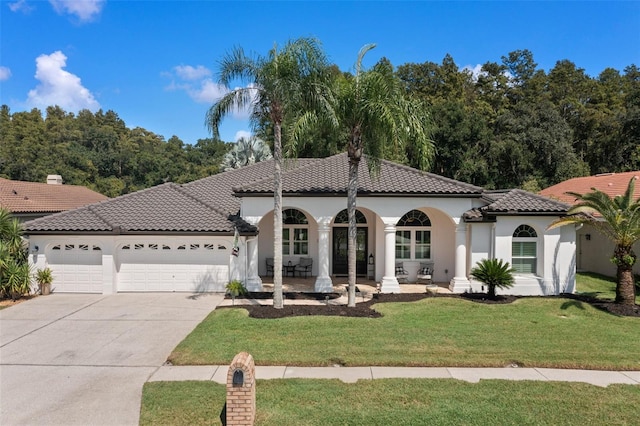 mediterranean / spanish house with a garage and a front lawn