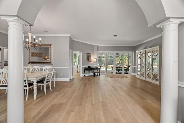 dining space featuring ornate columns, crown molding, a notable chandelier, and light hardwood / wood-style floors