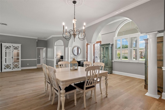 dining space featuring crown molding, decorative columns, and light wood-type flooring