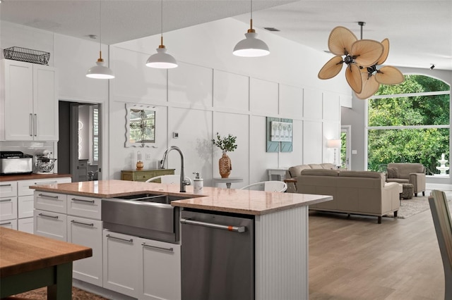 kitchen with a high ceiling, stainless steel dishwasher, white cabinets, and light stone counters