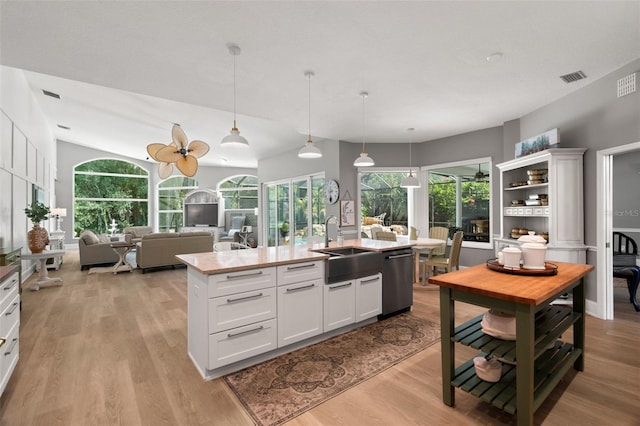 kitchen featuring sink, white cabinetry, a center island with sink, decorative light fixtures, and stainless steel dishwasher