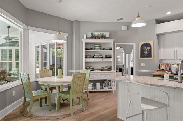 dining room with sink, light hardwood / wood-style flooring, and ceiling fan